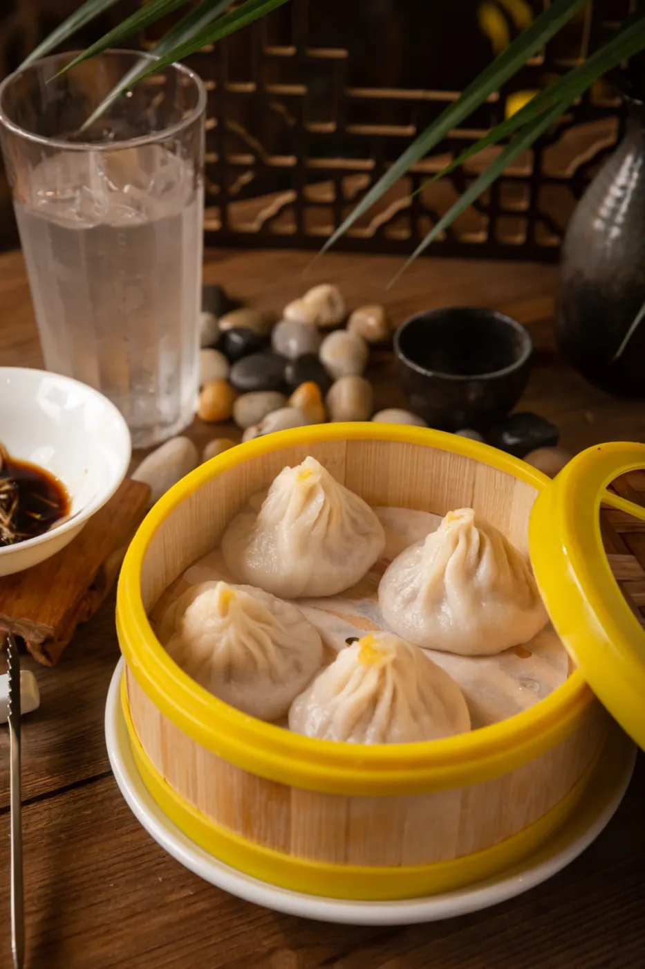 Soup dumplings with delicate pleats, resting in a bamboo steamer